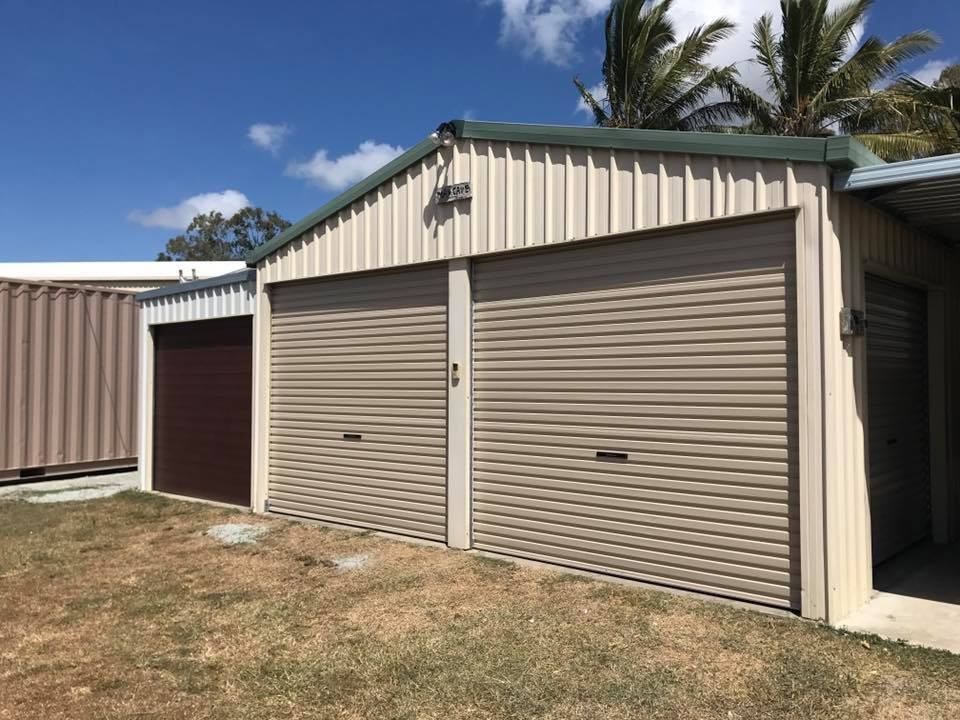 A Garage With Two Garage Doors and a Container in the Background — Mackay Garage Doors in Andergrove, QLD