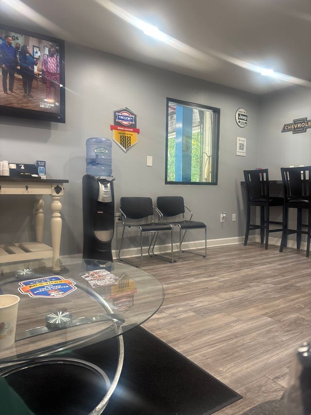 Waiting area with chairs, counter, wall art, and patterned carpet in a gray room | All 4 Tires