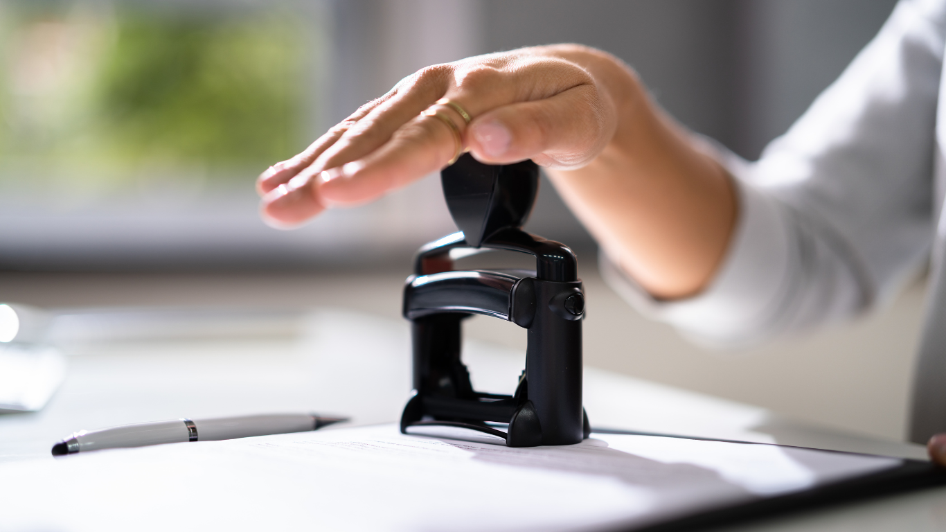 A person is putting a stamp on a piece of paper.