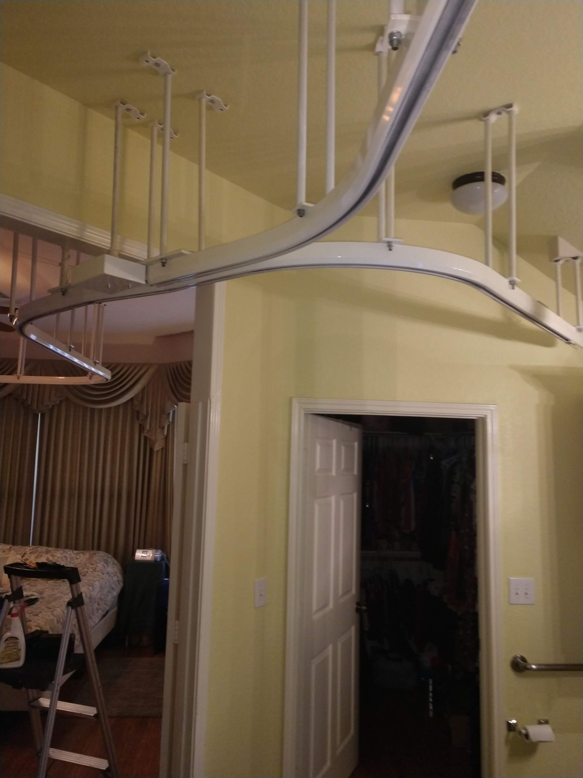 White curved ceiling-mounted curtain track with supports, above a doorway.