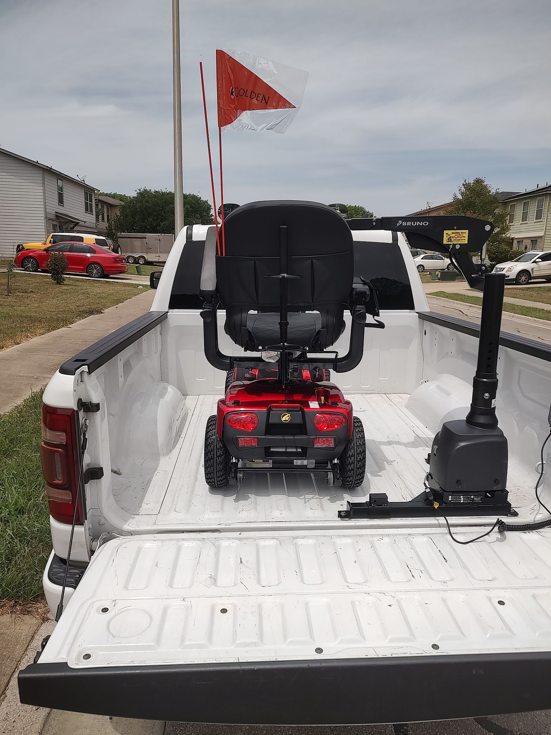 Red mobility scooter in white pickup truck bed with lift.