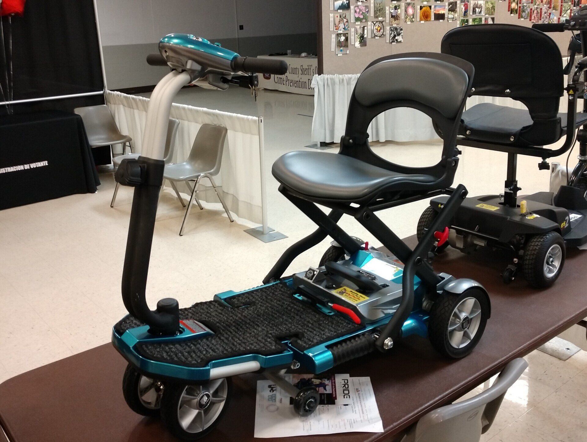 An electric wheelchair with a gardening attachment is parked inside a building. 