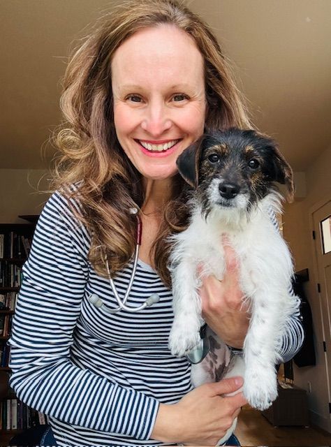 A woman is holding a small dog in her arms and smiling.
