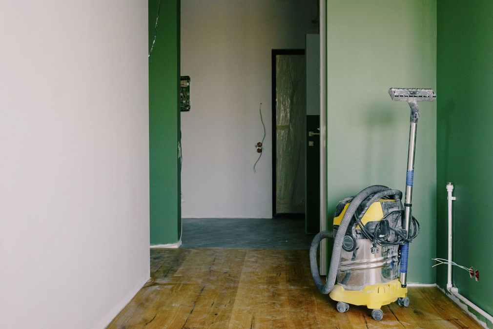 Empty hallway with a floor sander near a green wall and doorway