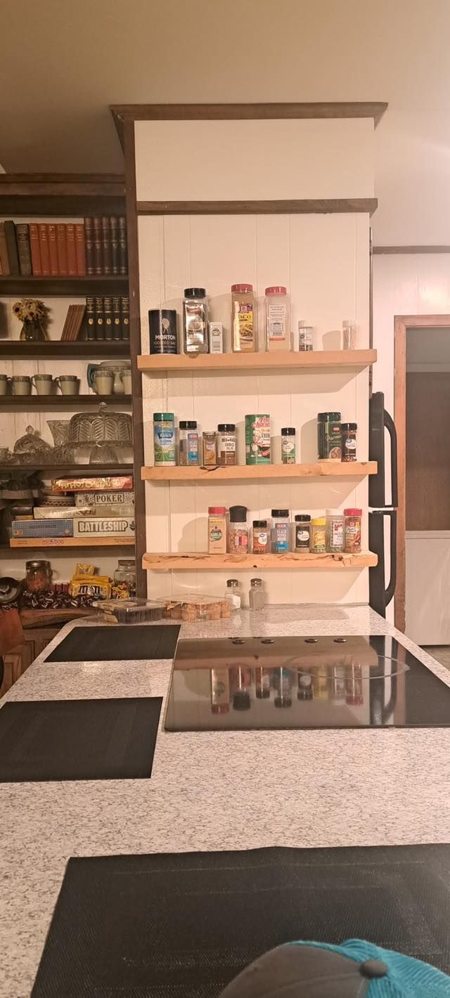Kitchen with floating shelves holding spice jars. A black and white checkered countertop is in the foreground.