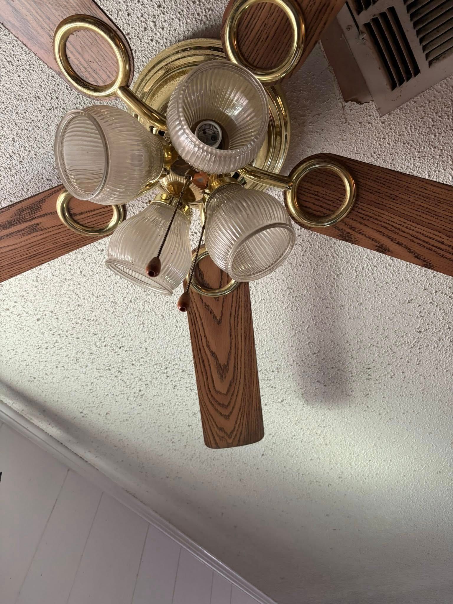 Ceiling fan with wooden blades, gold accents, and globe lights.