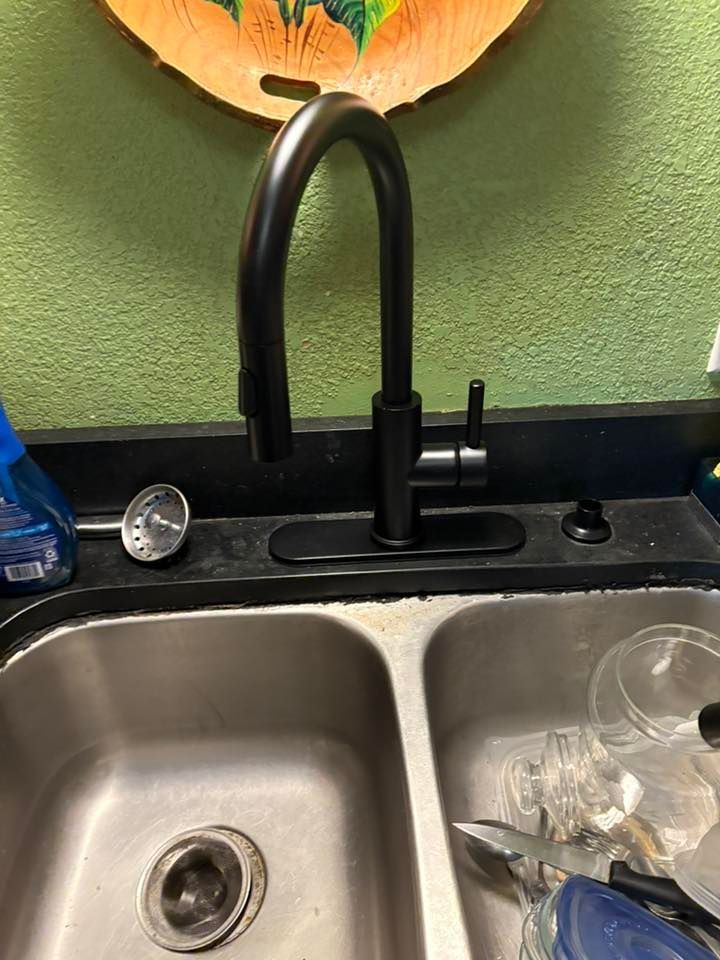 Black kitchen faucet over a stainless steel double sink.