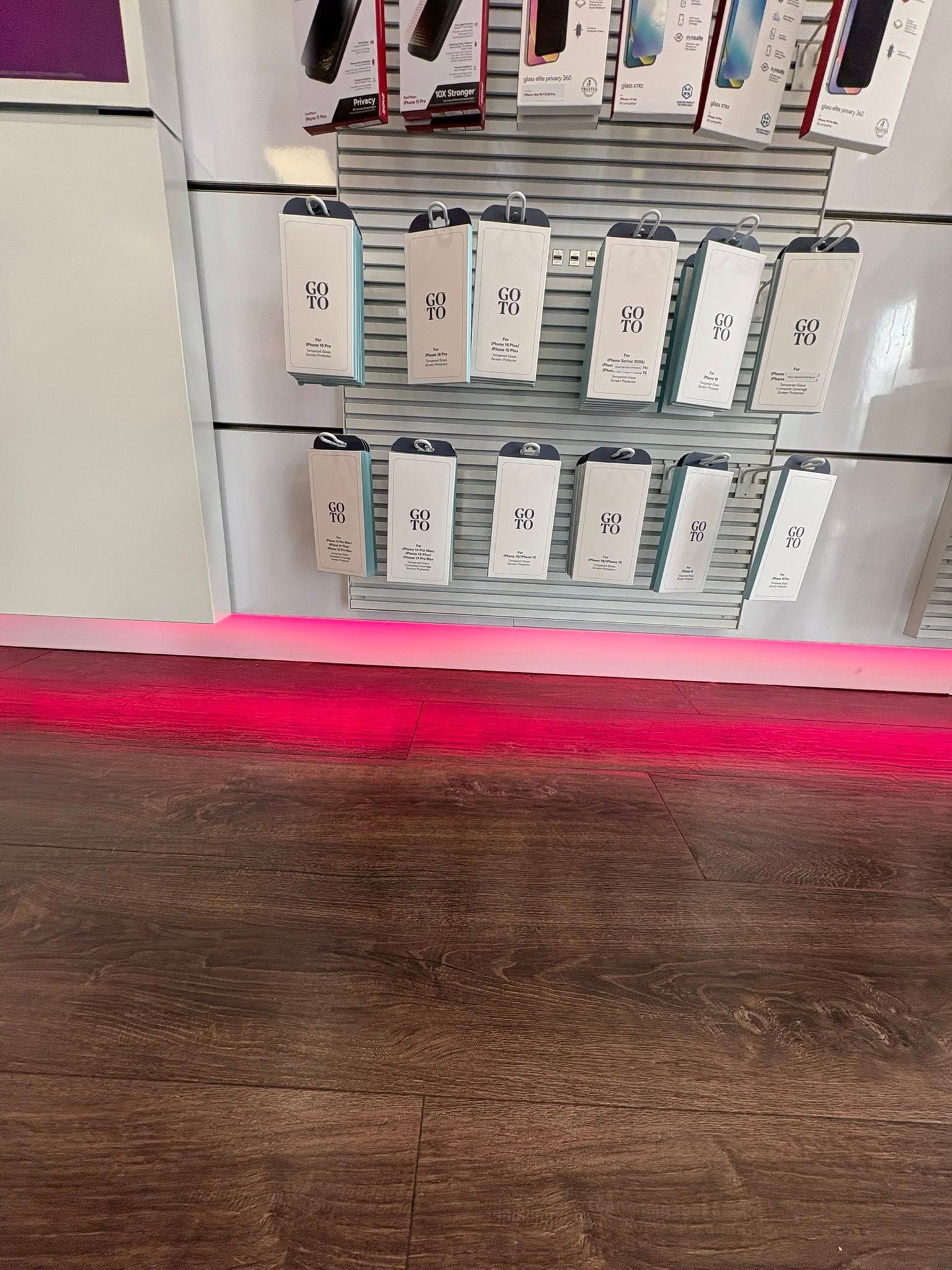 Cell phone accessories displayed on a store shelf, with a red light on the counter below.