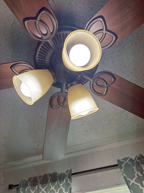 Ceiling fan with three lights, brown blades, and decorative metal accents.