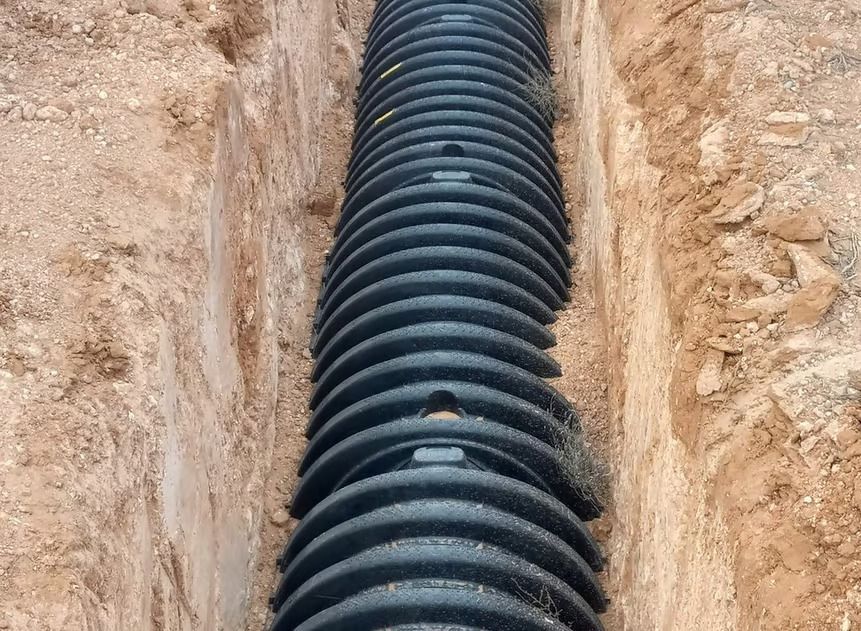 A large black pipe is laying in the dirt