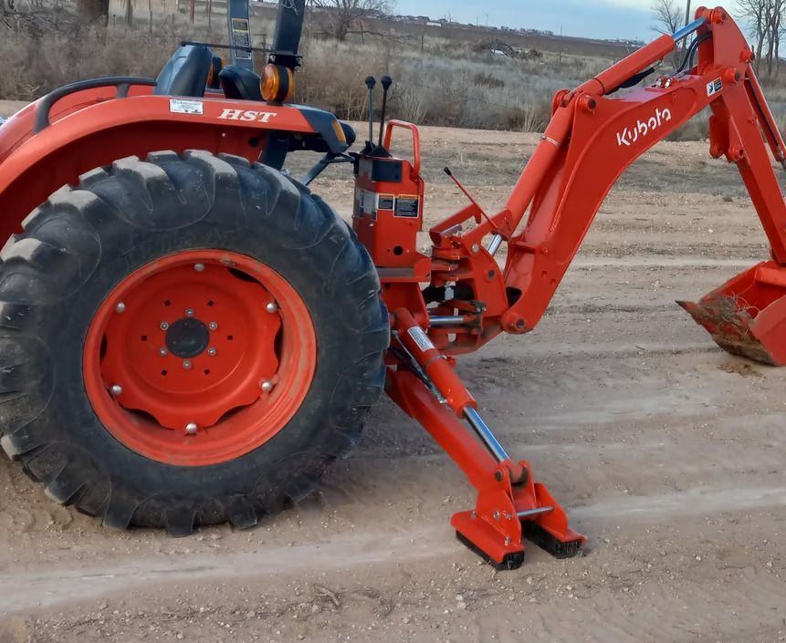 A kubota tractor is parked in a dirt field