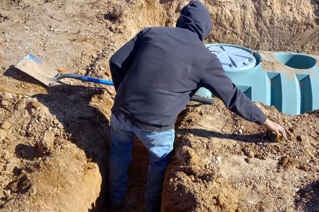 A man is digging in the dirt with a shovel.