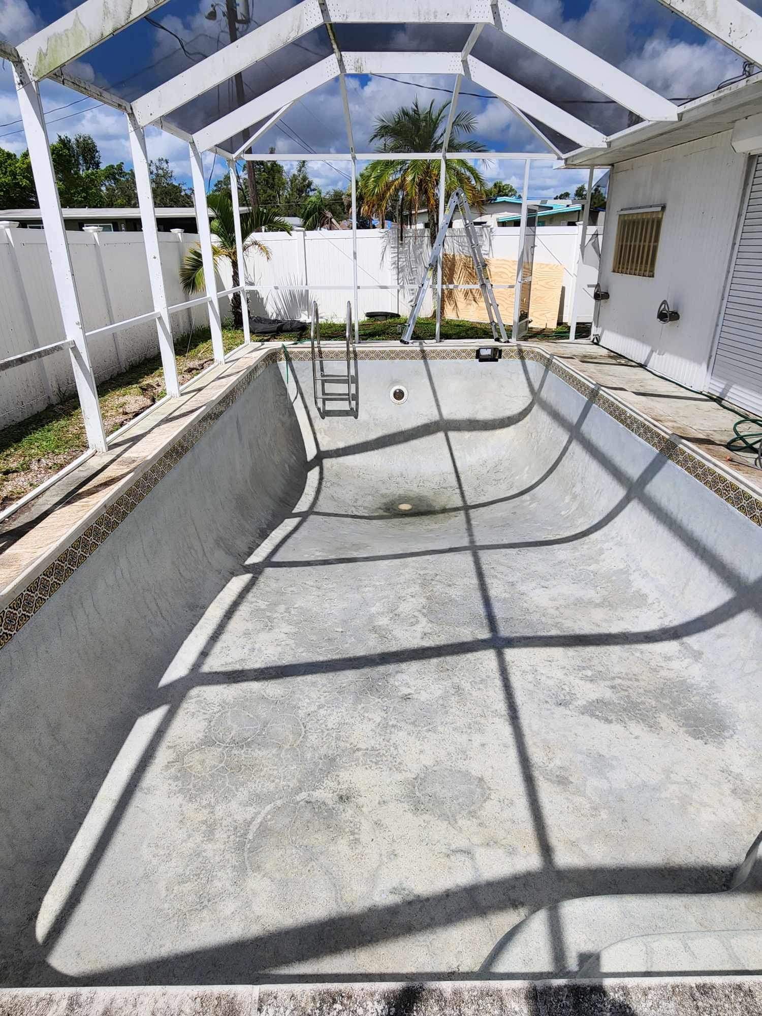 An empty swimming pool under a canopy in a backyard.