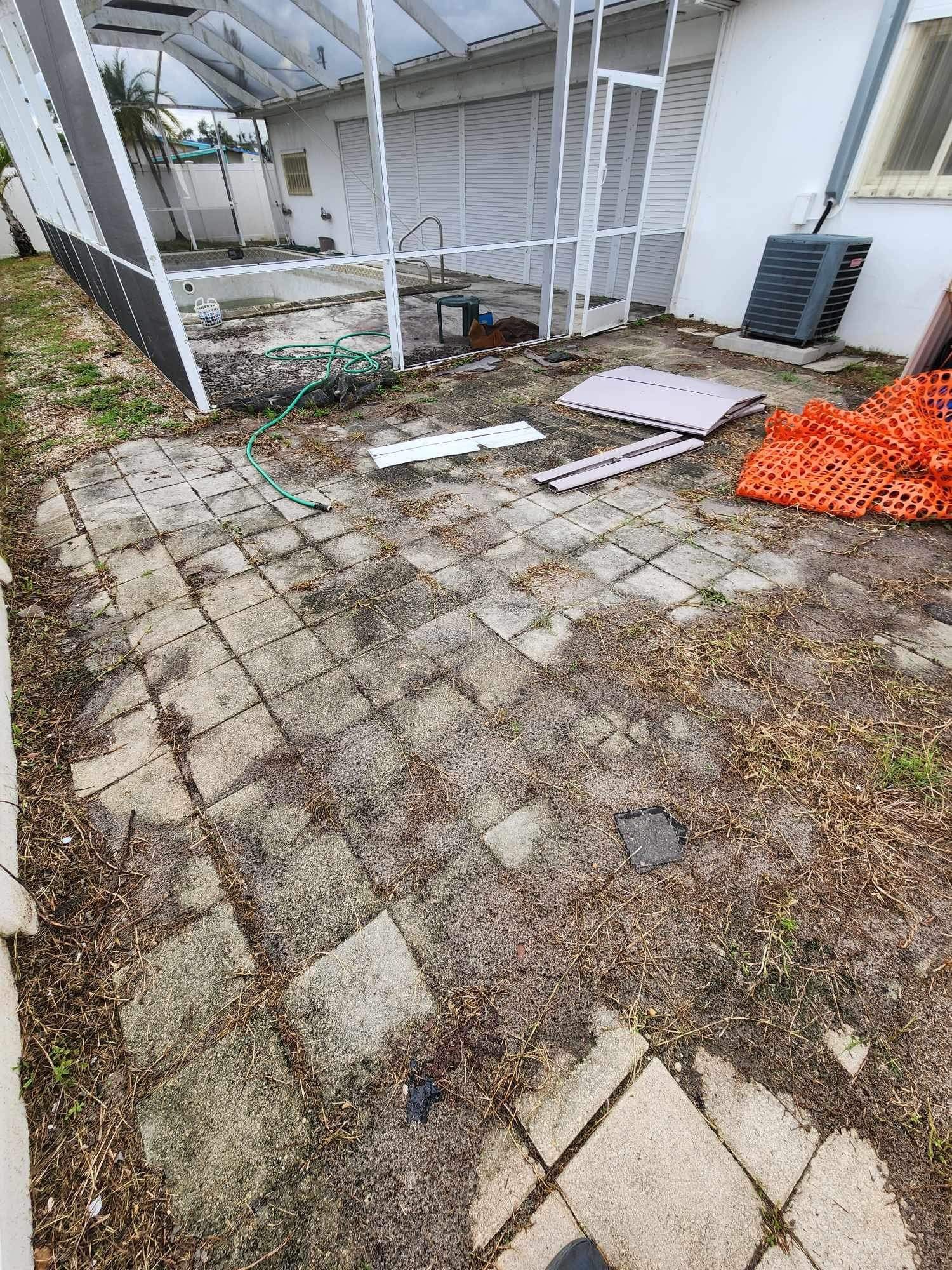 A patio with a lot of trash on it in front of a house.
