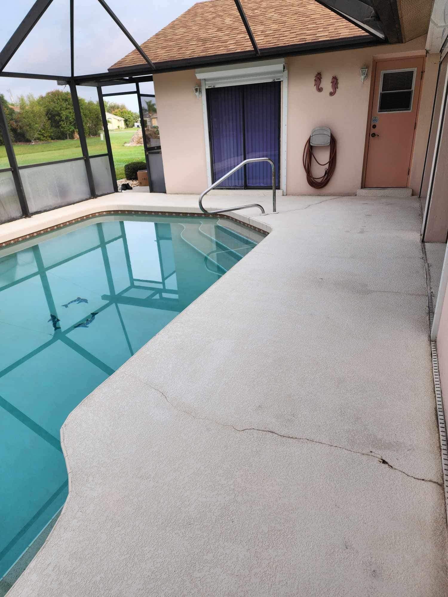 A large swimming pool is surrounded by a screened in area