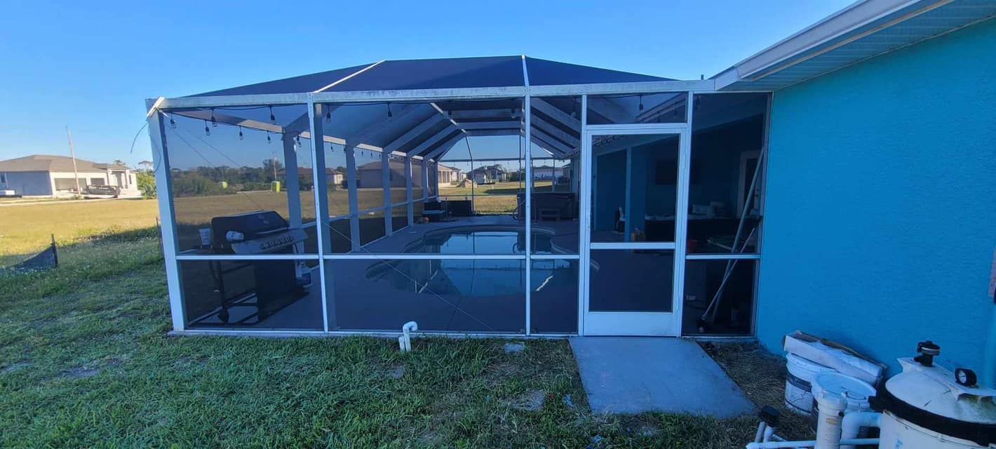 A screened in porch with a pool in the backyard of a house.