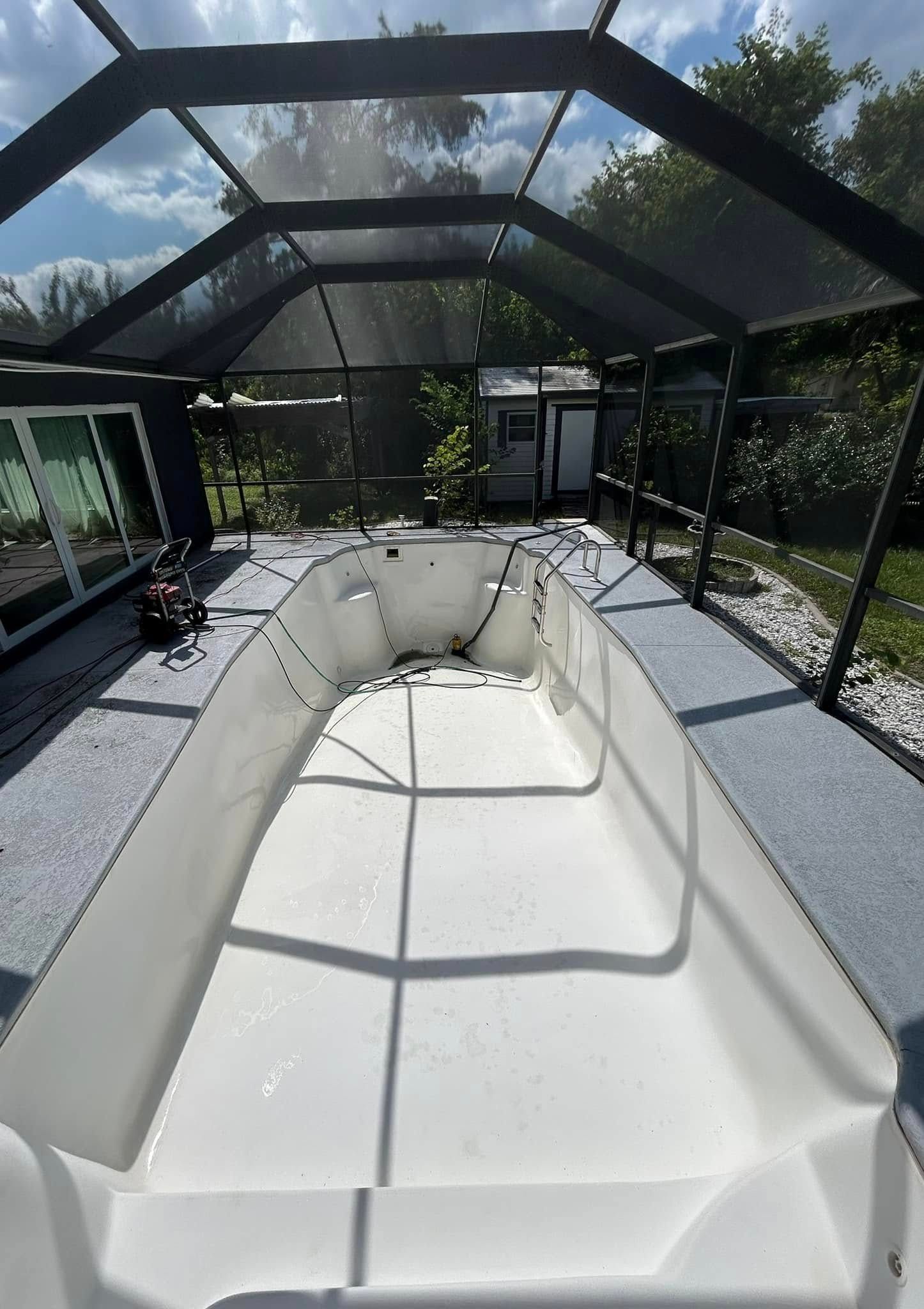 A white boat is sitting under a clear roof in a swimming pool.