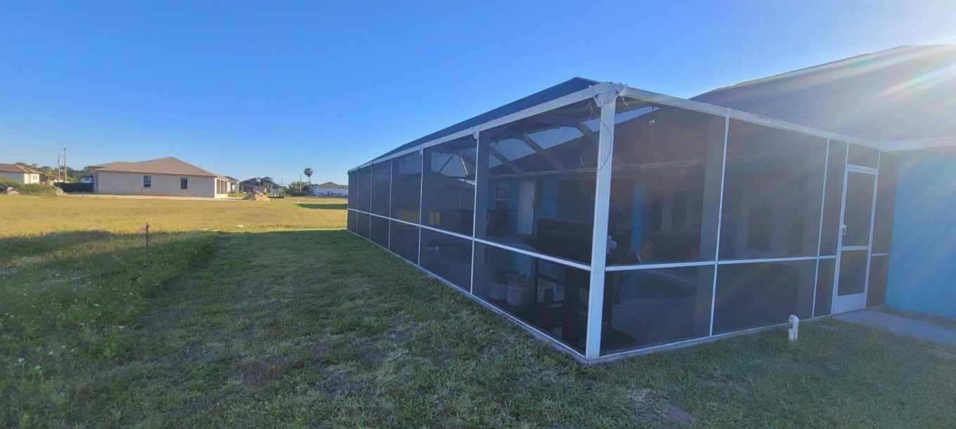 A screened in porch in the backyard of a house.