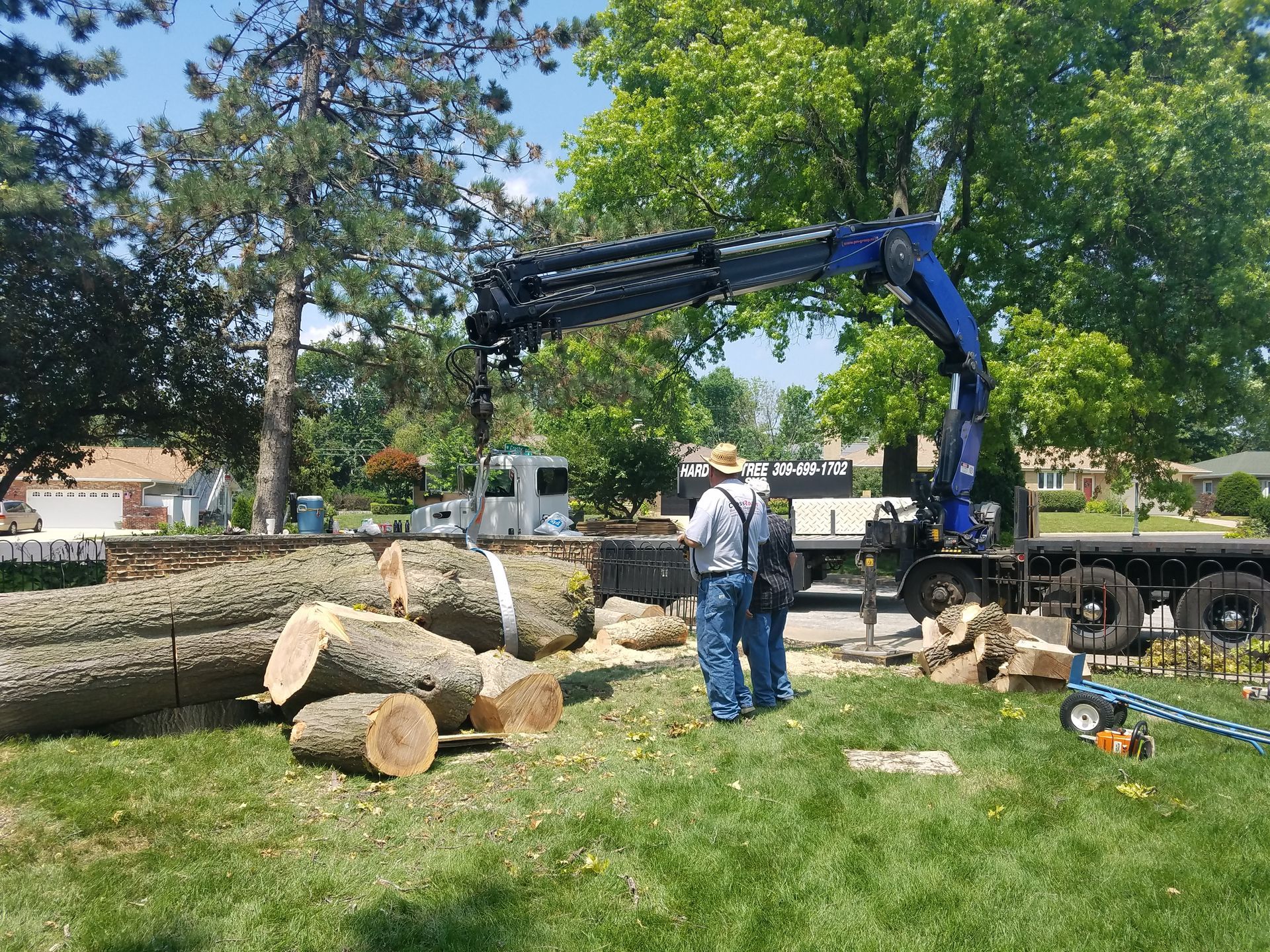 A man is standing in front of a truck with a crane attached to it.