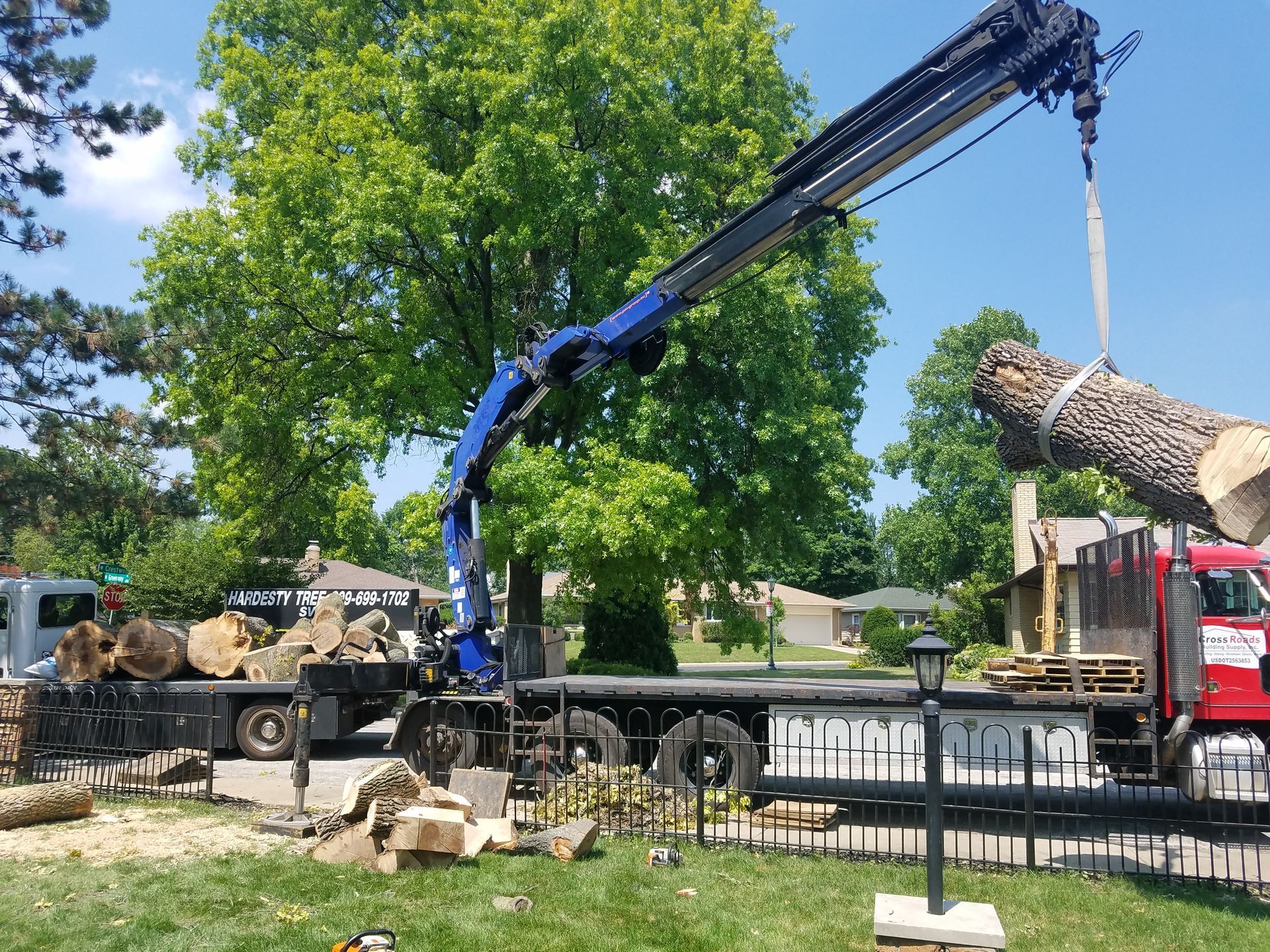 A crane is lifting a large log from a truck.