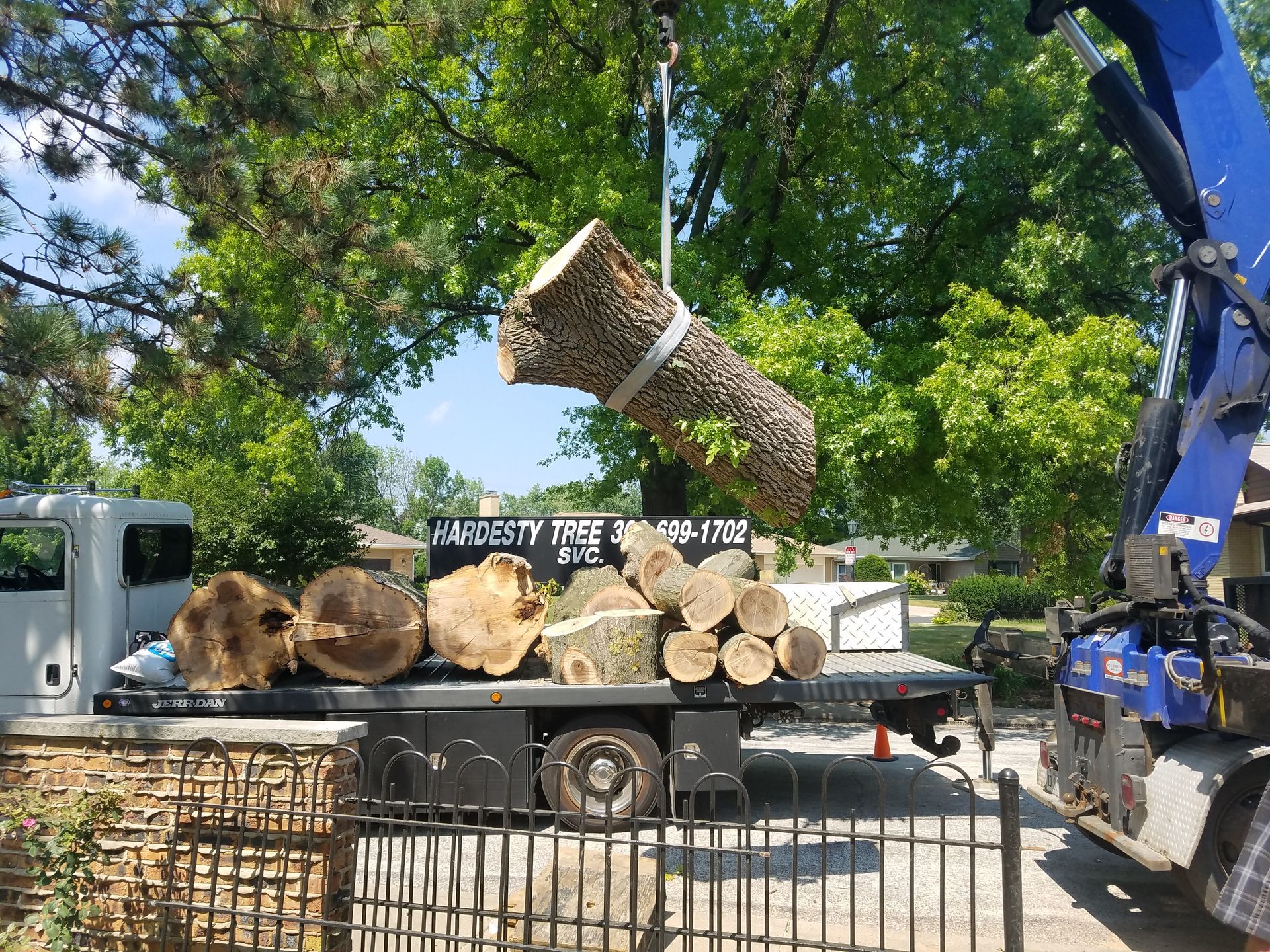 A crane is lifting a large log from a truck.