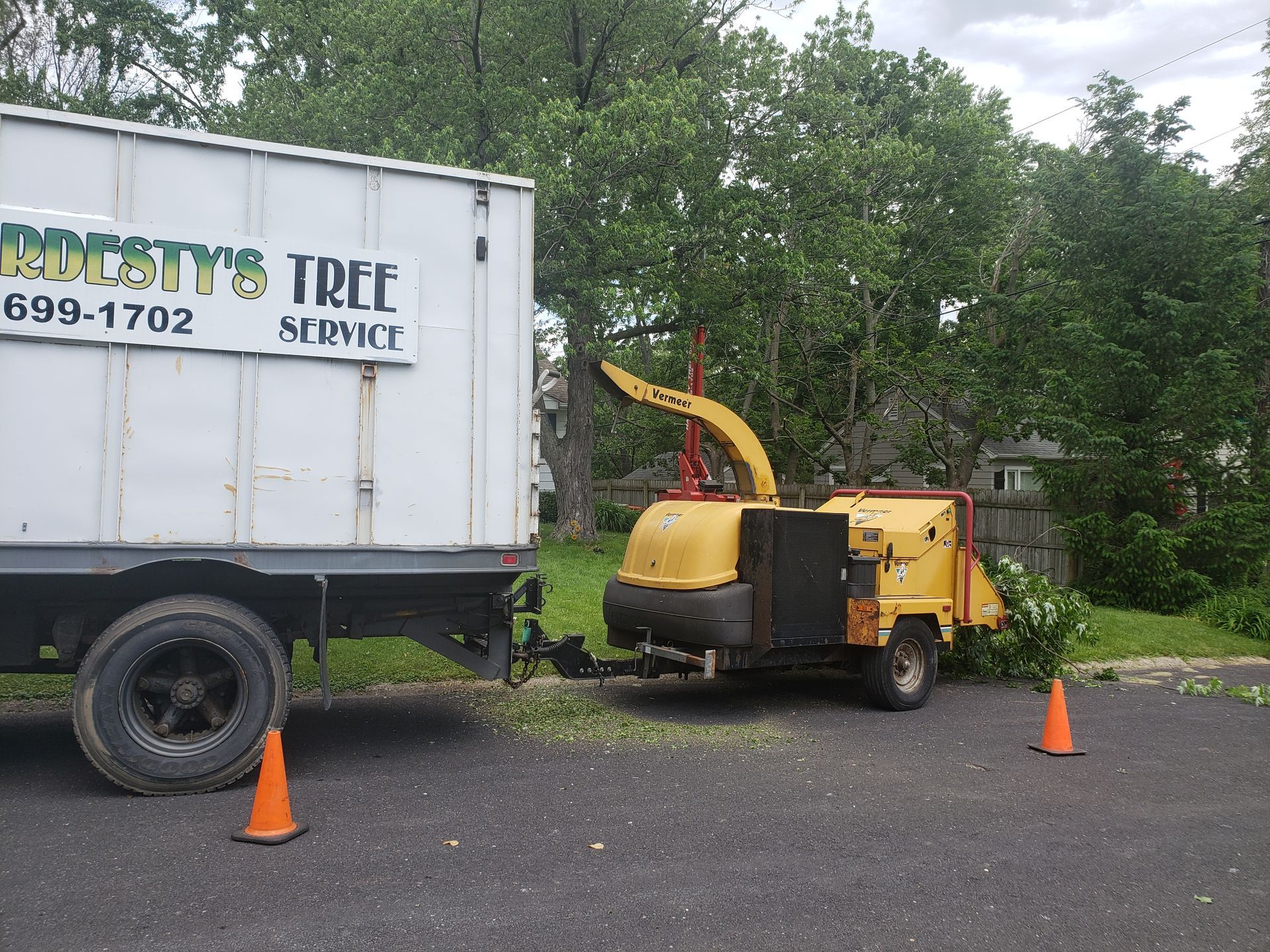 A tree service truck is parked next to a tree chipper