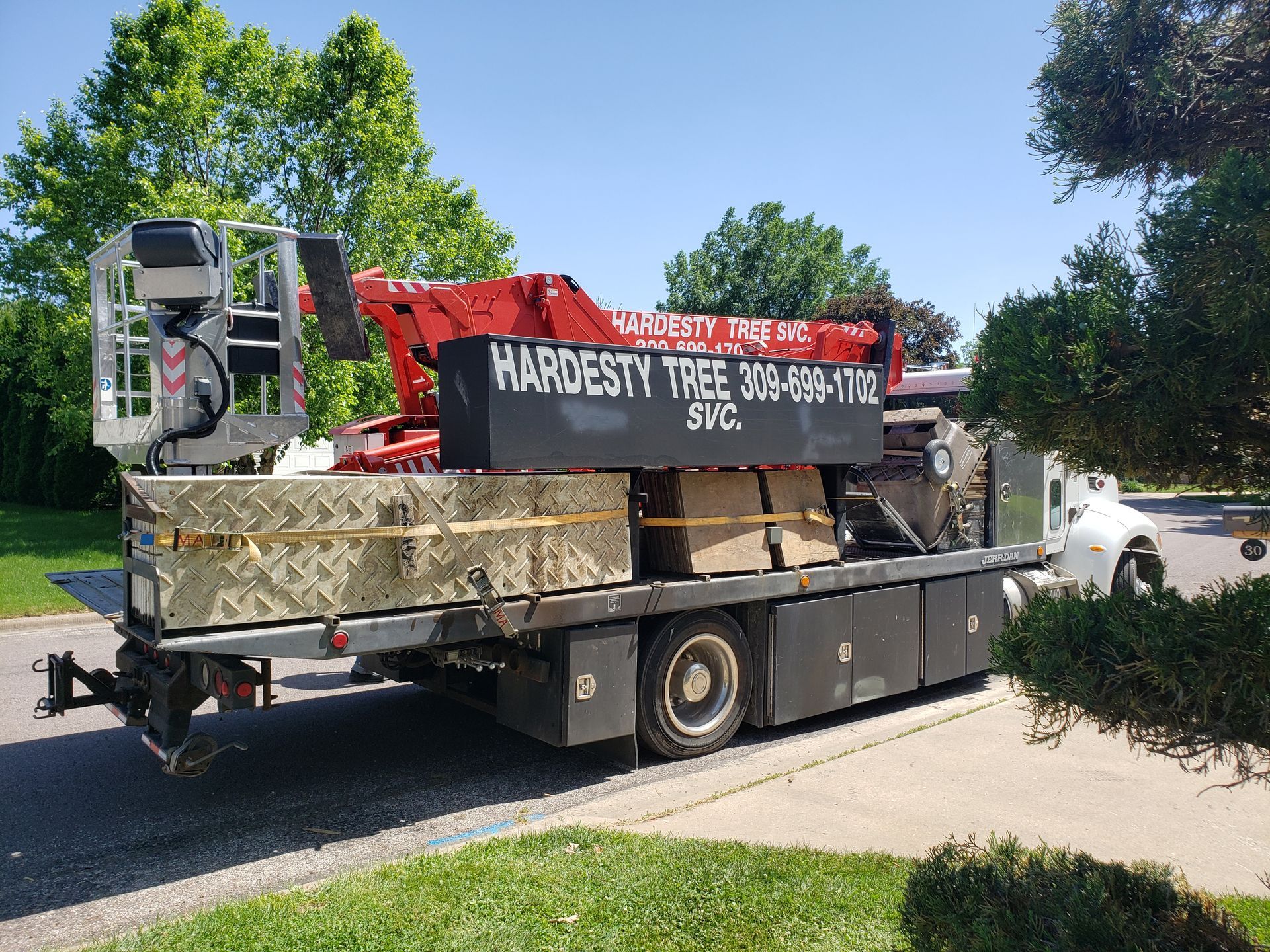 A tow truck with a crane on the back is parked on the side of the road.