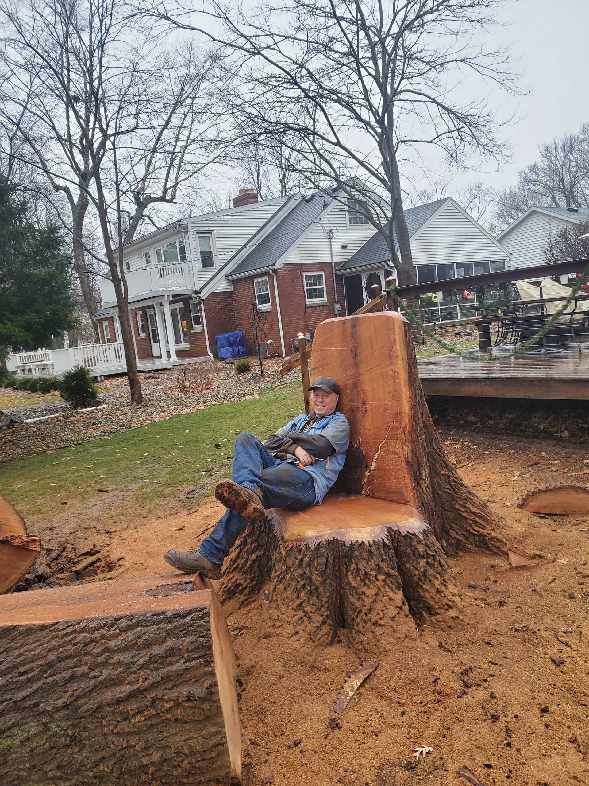 A man is sitting in a chair made out of a tree stump.