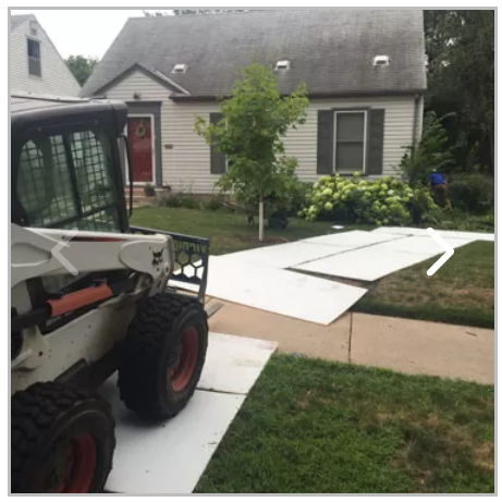 A bobcat is parked in front of a house