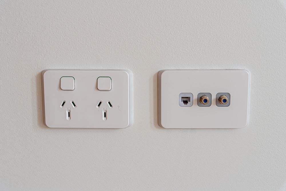 White electrical wall outlets on a white wall. One with power plugs, the other with data ports — Holders Electrical In Tenterfield, NSW