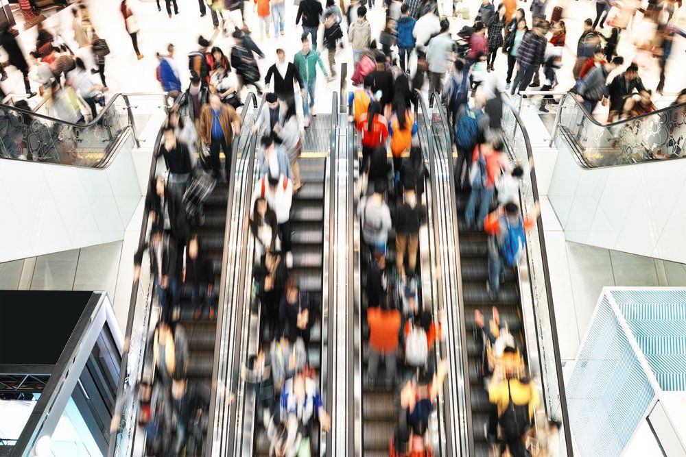 A large group of people are riding escalators in a mall.