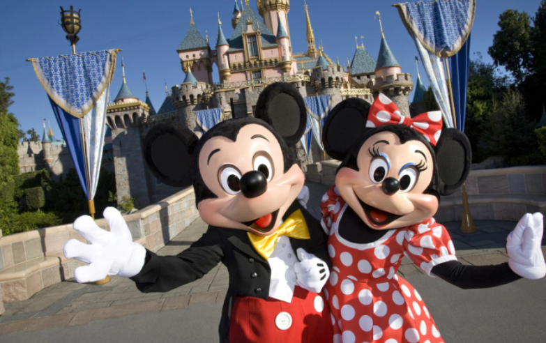 Mickey mouse and minnie mouse are standing in front of a castle