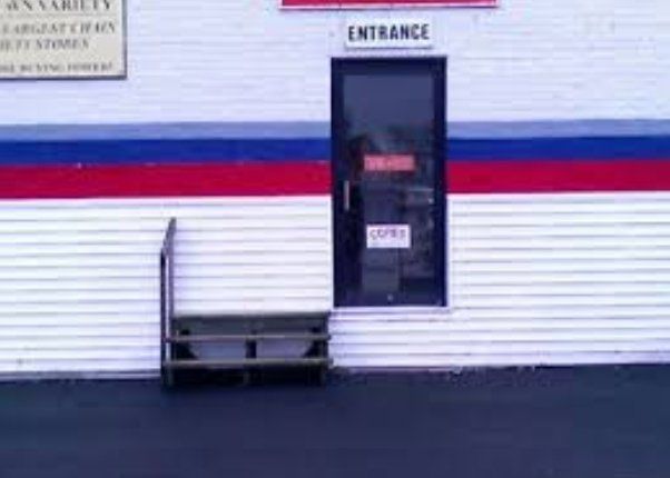 A white building with a red blue and white stripe and a sign that says entrance