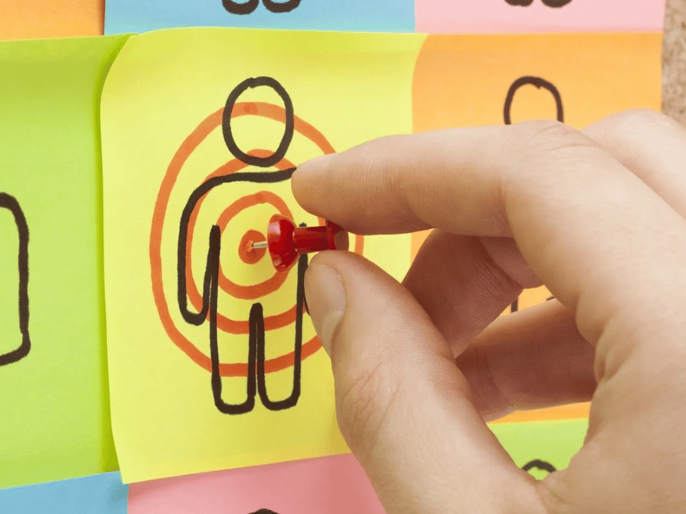 A person is pointing at a target with a red pin