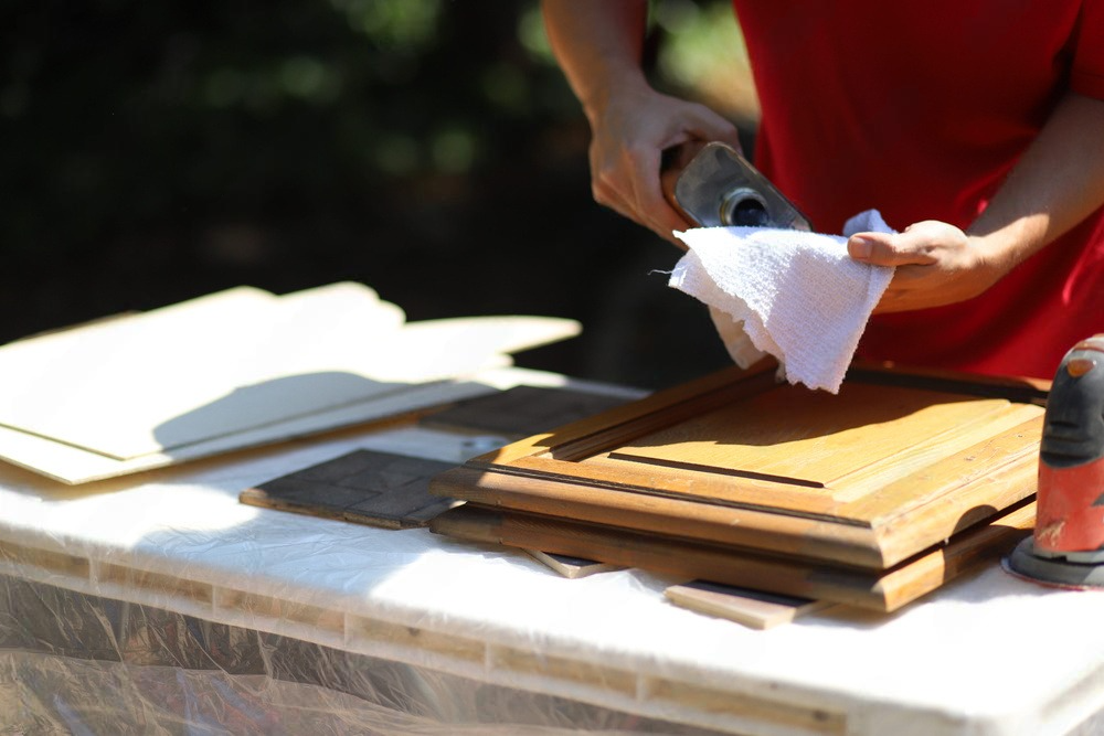 a person cleaning a piece of wood with a towel