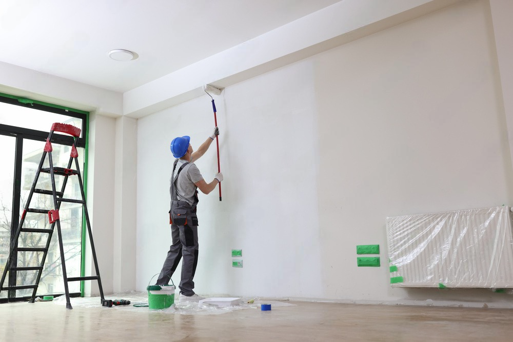 a man is painting a wall with a roller