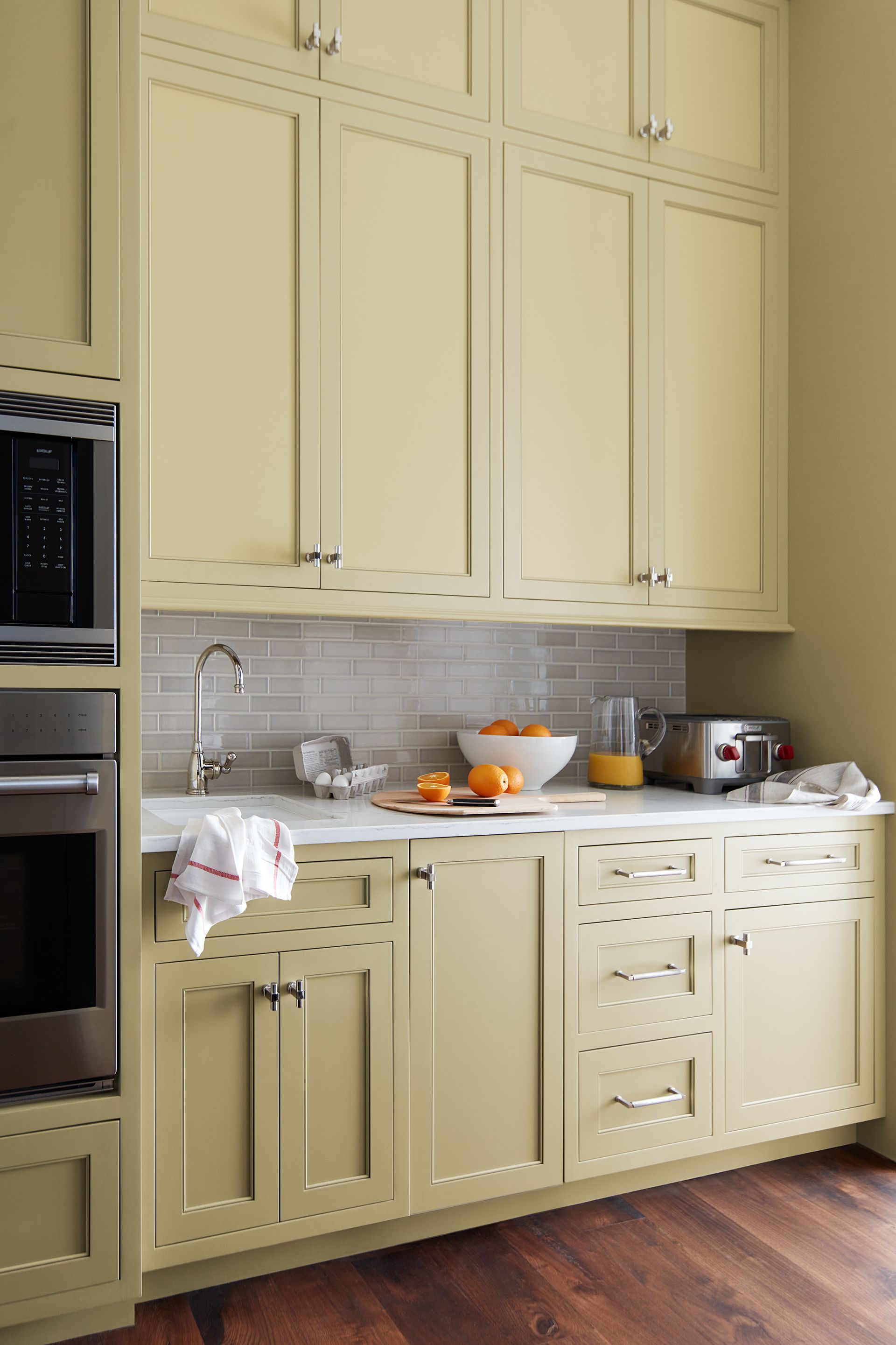 A kitchen with yellow cabinets and stainless steel appliances