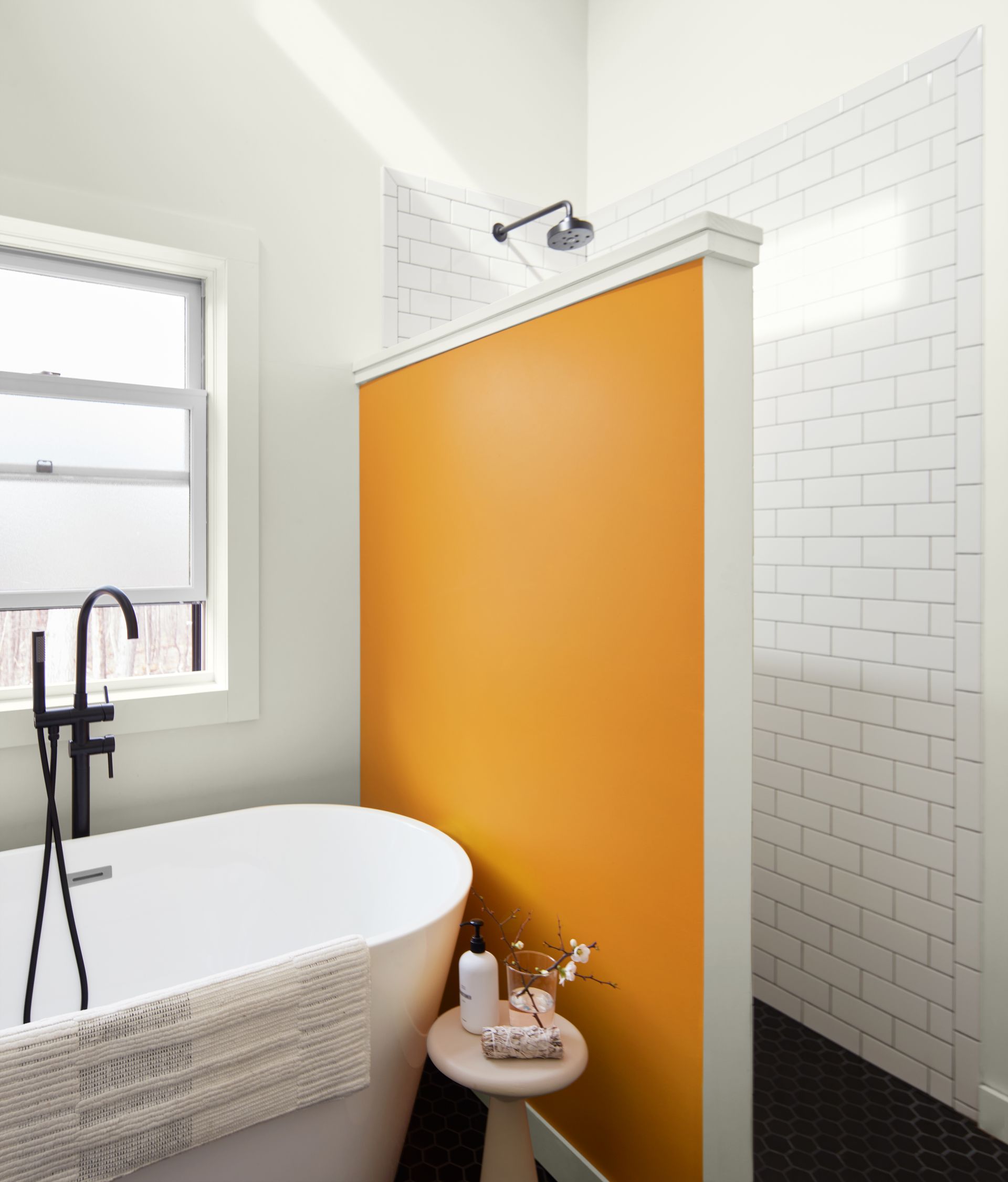 A bathroom with an orange wall and a white tub