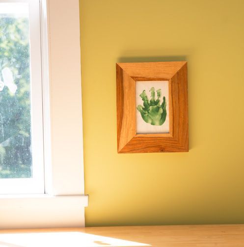 A picture of a child 's hand in a wooden frame