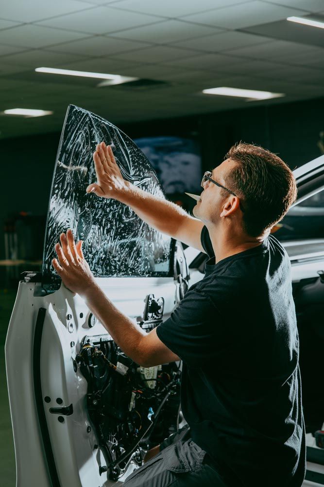 A man is applying window tinting to a car window.