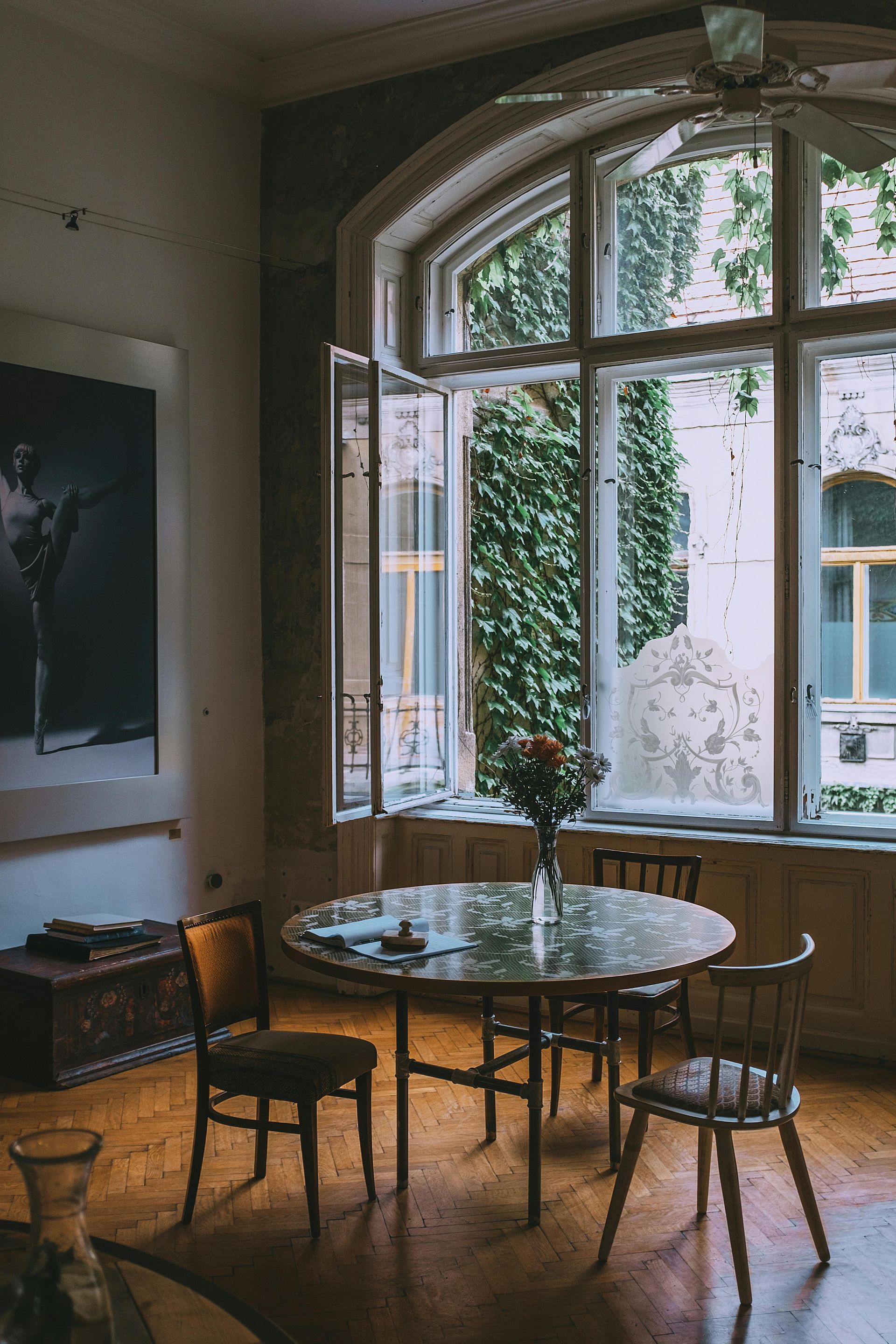 A dining room with a table and chairs in front of a large window.