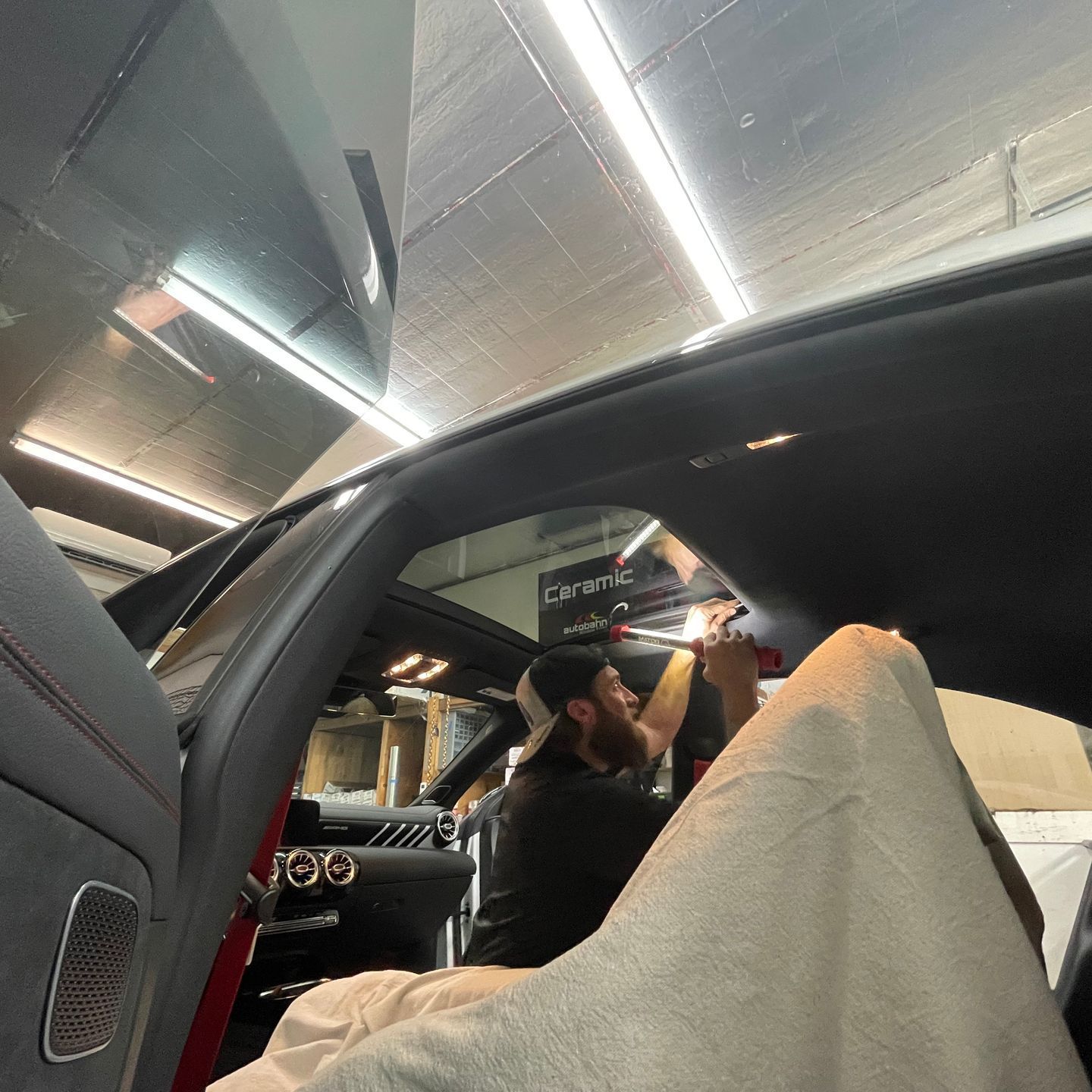 A person is cleaning a car with a pink squeegee.