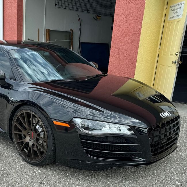 A car is covered in plastic wrap in a garage.