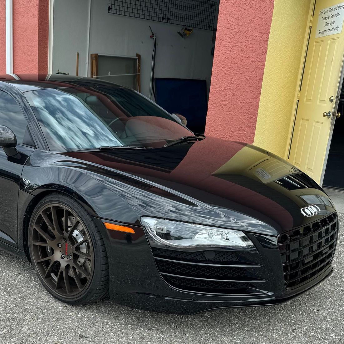 A black audi r8 is parked in front of a garage