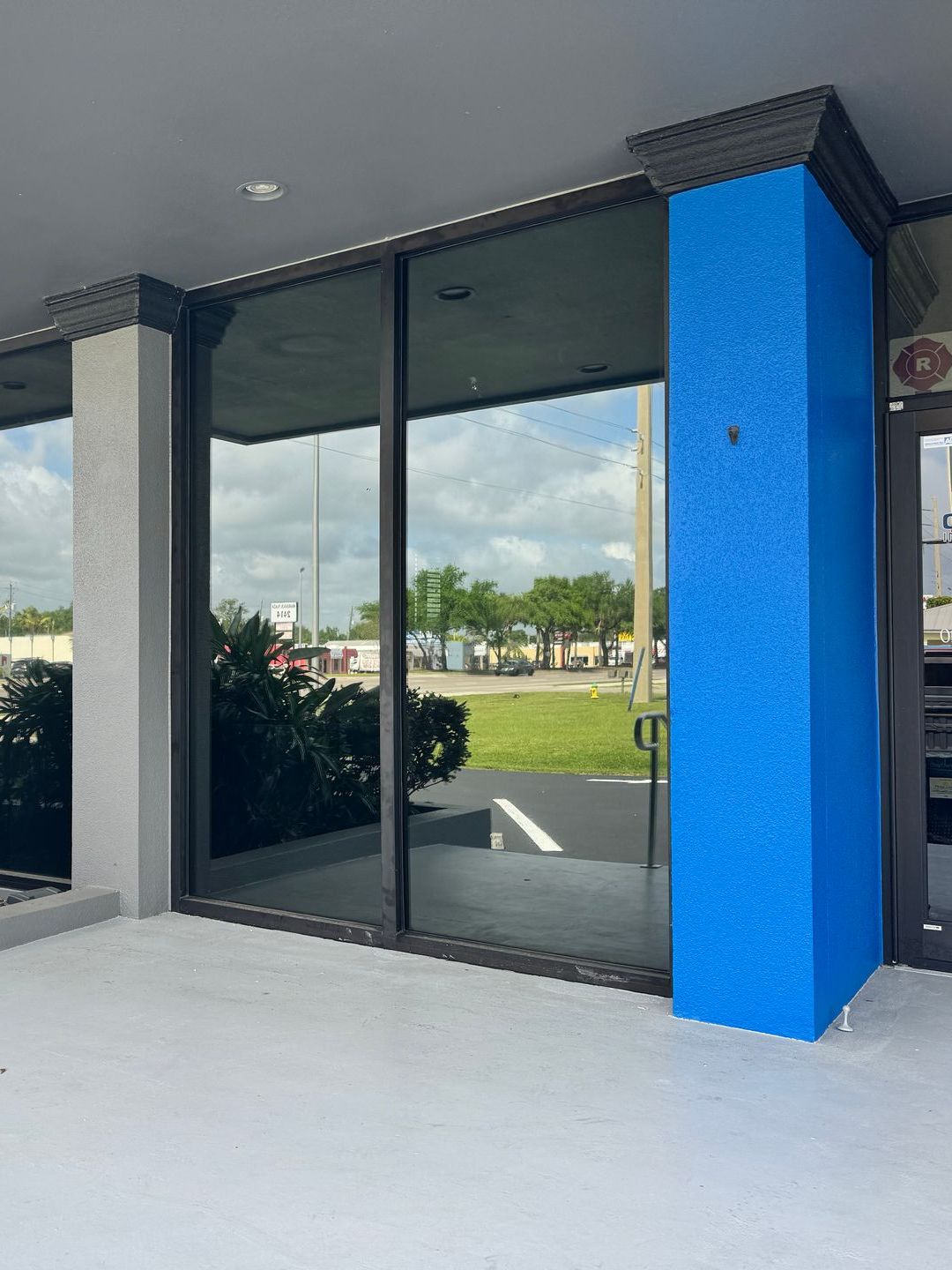 A blue pillar is in front of a building with a lot of windows.