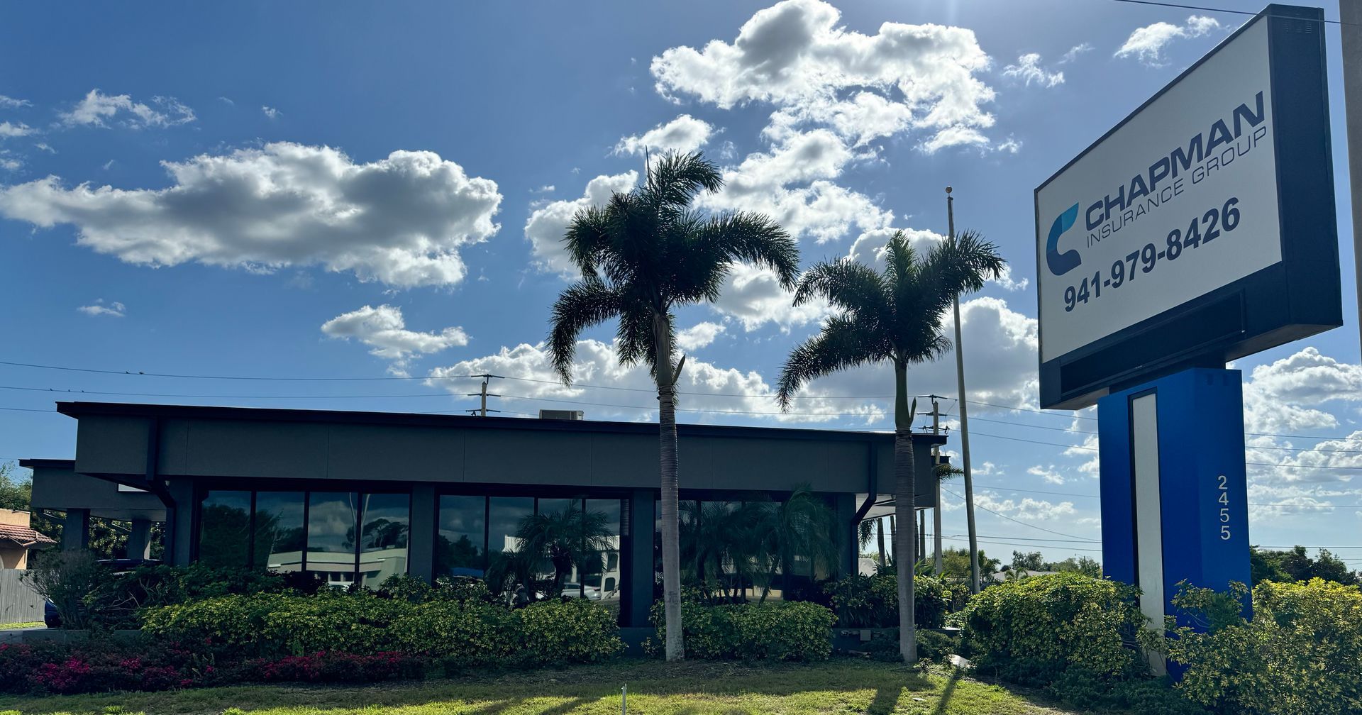 A building with a sign in front of it and palm trees.