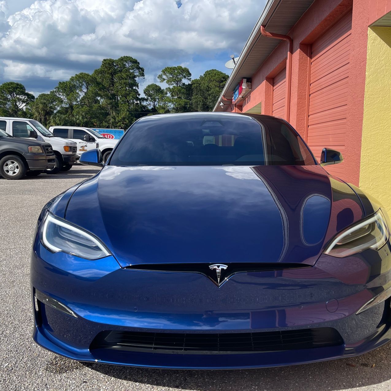 A blue tesla model s is parked in front of a building