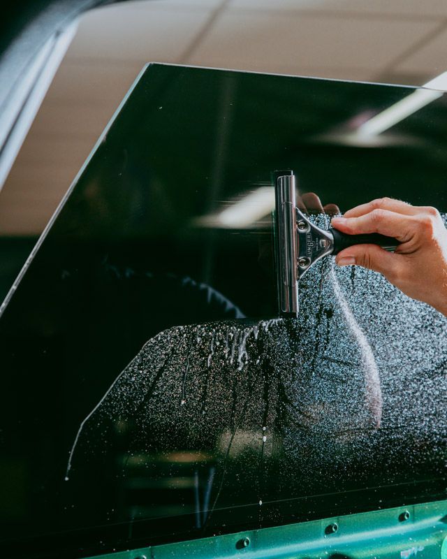 A person is cleaning a car window with a squeegee.