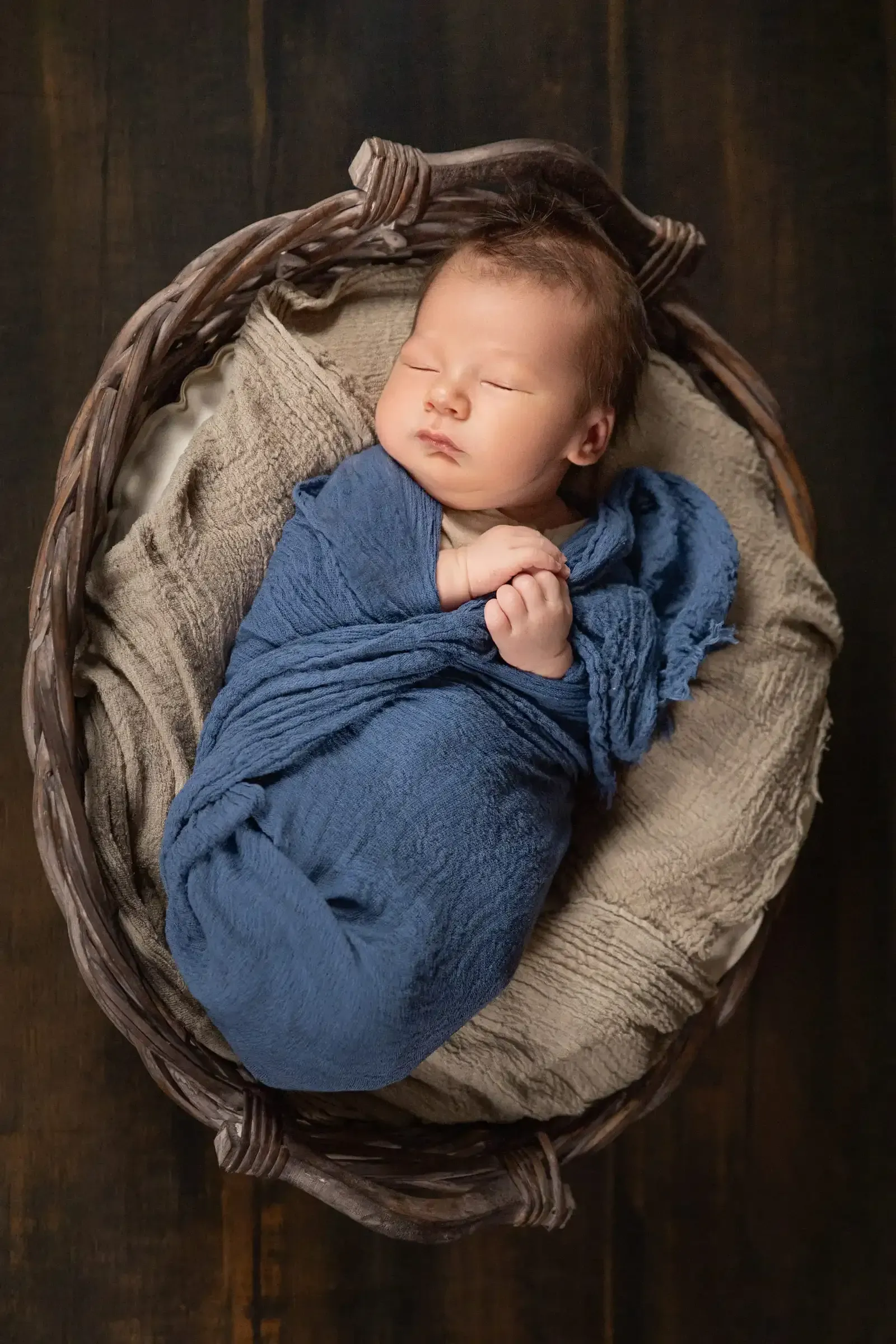 Newborn Shooting im Korb mit einer blauen Decke