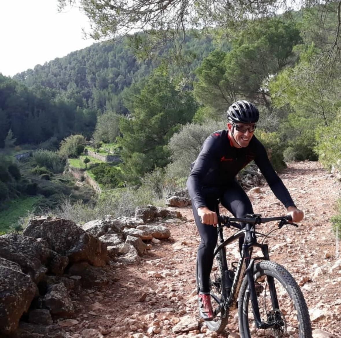 Un hombre en bicicleta de montaña recorre un sendero rocoso en un bosque.